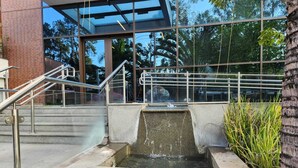 Un bâtiment moderne doté d’une façade en verre, d’un escalier extérieur et d’un petit élément décoratif aquatique.