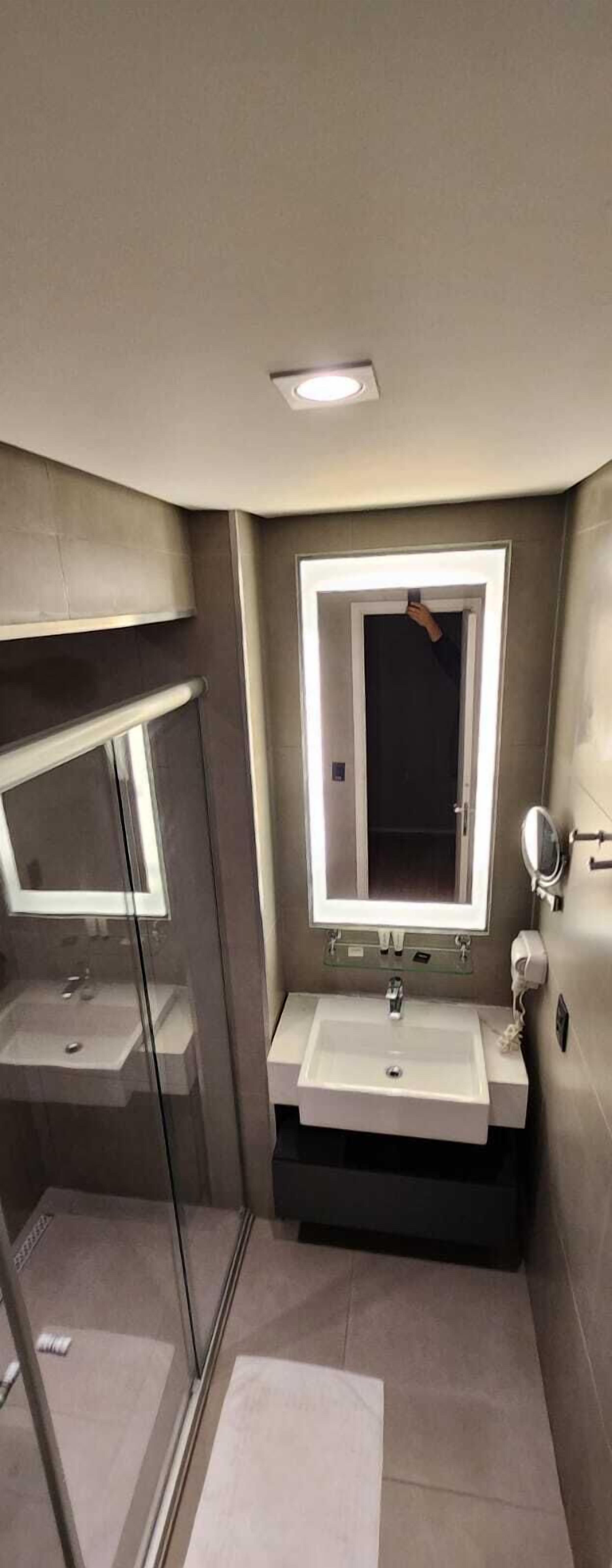A modern bathroom with a glass shower enclosure, a vanity with a mirror, and a sink.
