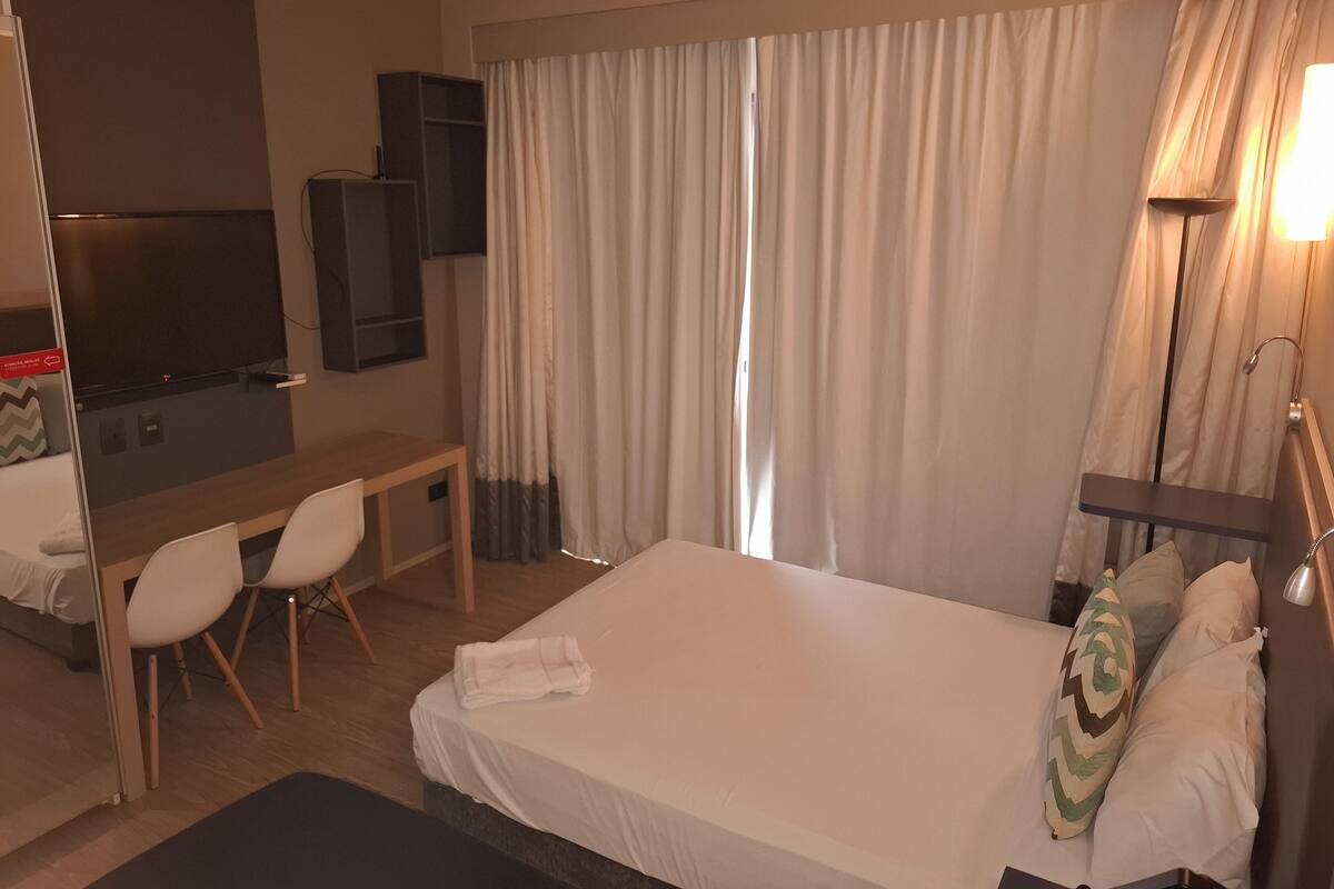 Une chambre d’hôtel équipée d’un lit, d’un bureau, d’une chaise, d’une télévision et d’un espace douche.