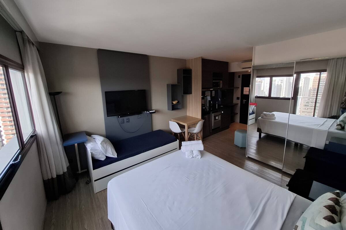 Une chambre d’hôtel équipée d’un lit, d’un bureau, d’une télévision, d’une kitchenette et d’une salle de bain.