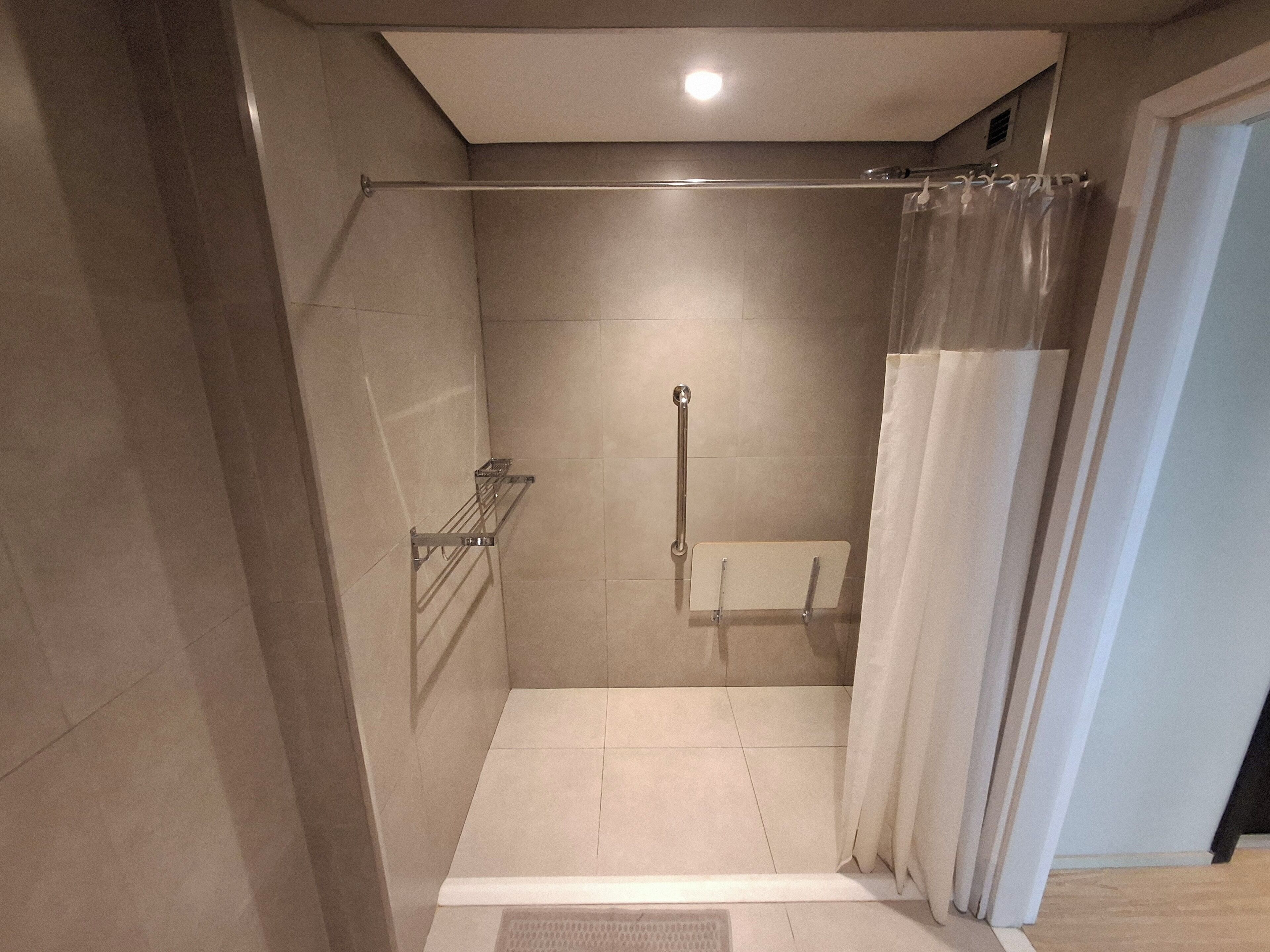 A modern bathroom with a shower, a towel rack, and a toilet.