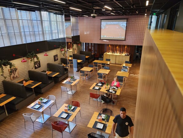 Un restaurante moderno con mesas de madera y asientos acolchados negros.