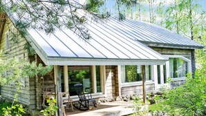 A rustic cabin with a covered porch, stone foundation, and a metal roof. - Ateljee by Interhome (Rääkkylä)