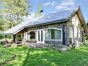 A rustic log cabin with a stone foundation, large windows, and a metal roof. - Ateljee by Interhome (Rääkkylä)