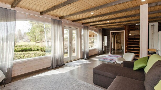 A spacious living room with a large window, a sofa, and a chair. - Ateljee by Interhome (Rääkkylä)