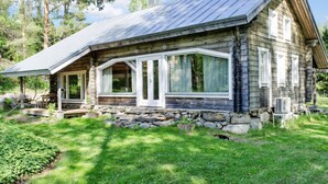 A rustic log cabin with a stone foundation, large windows, and a metal roof. - Ateljee by Interhome (Rääkkylä)