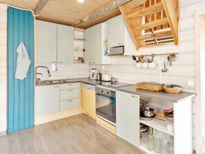 A kitchen with wooden cabinets, a built-in oven, and a wooden ceiling. - Ateljee by Interhome (Rääkkylä)