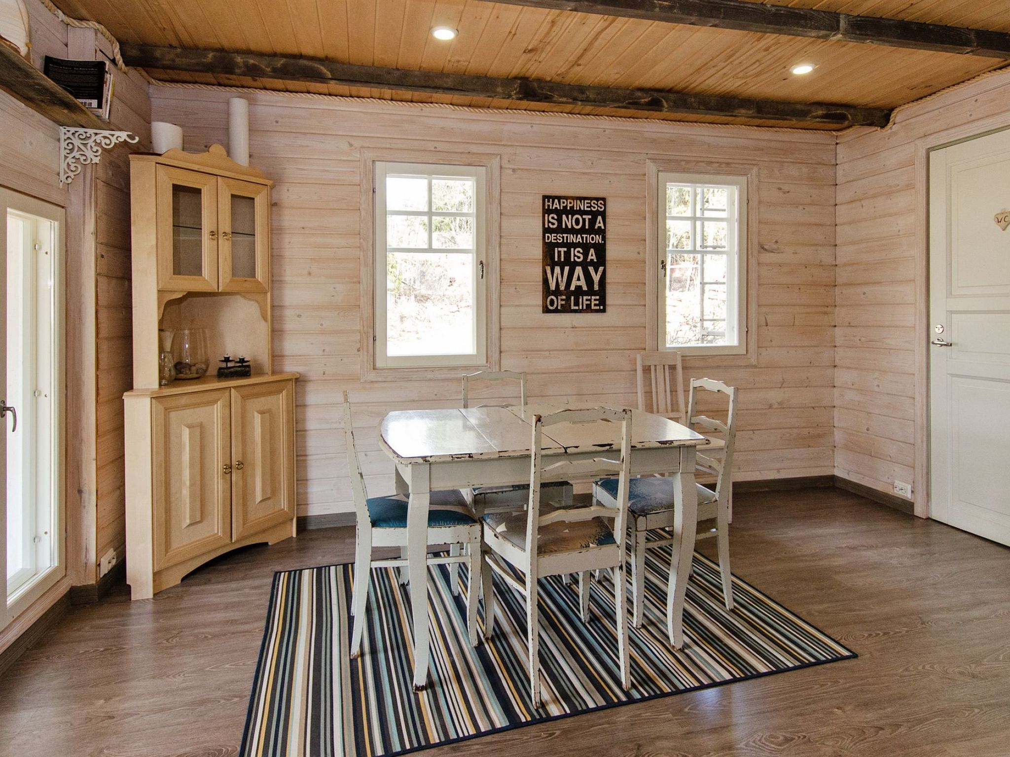 Un intérieur en bois comprenant une table et des chaises, un buffet et une citation inspirante sur le mur.