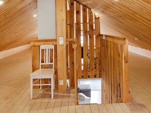 A room with a sloped ceiling, wooden floor, a white chair, and a small table. - Ateljee by Interhome (Rääkkylä)