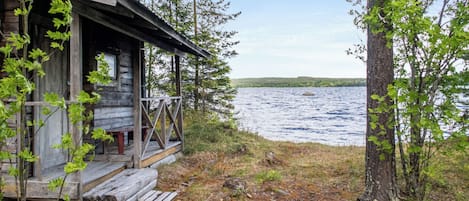 Ein rustikales Blockhaus mit einer Holzterrasse mit Blick auf einen See.
