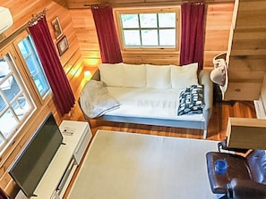A cozy cabin interior with a bed, a television, and a window with curtains. - Kotimökki by Interhome (Sotkamo)