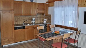 Una cocina con armarios de madera, una cafetera y una mesa de comedor con sillas.