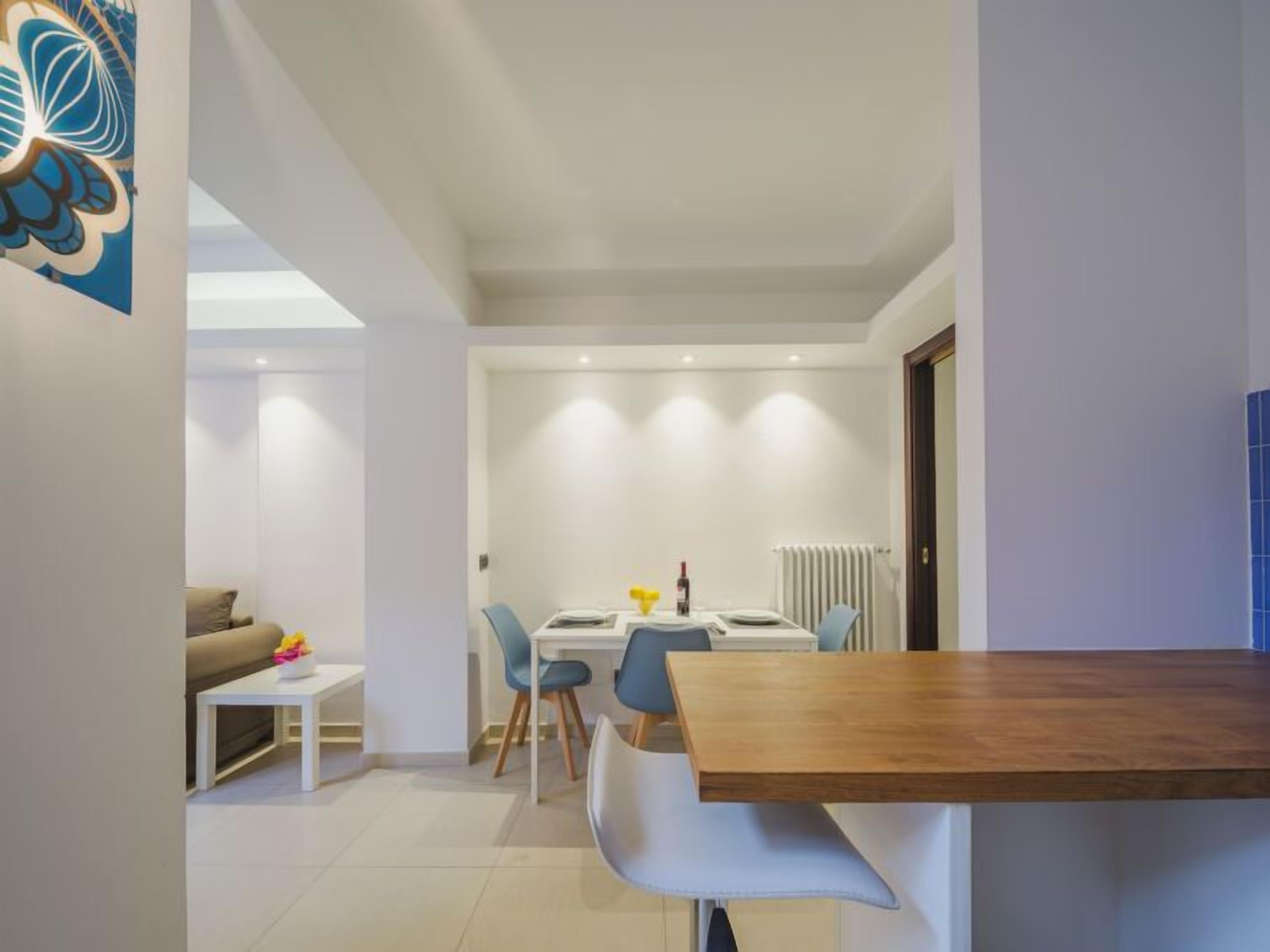 A modern living room with a sofa, a coffee table, and a dining area with a table and chairs.