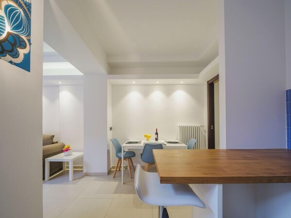 A modern living room with a sofa, a coffee table, and a dining area with a table and chairs.