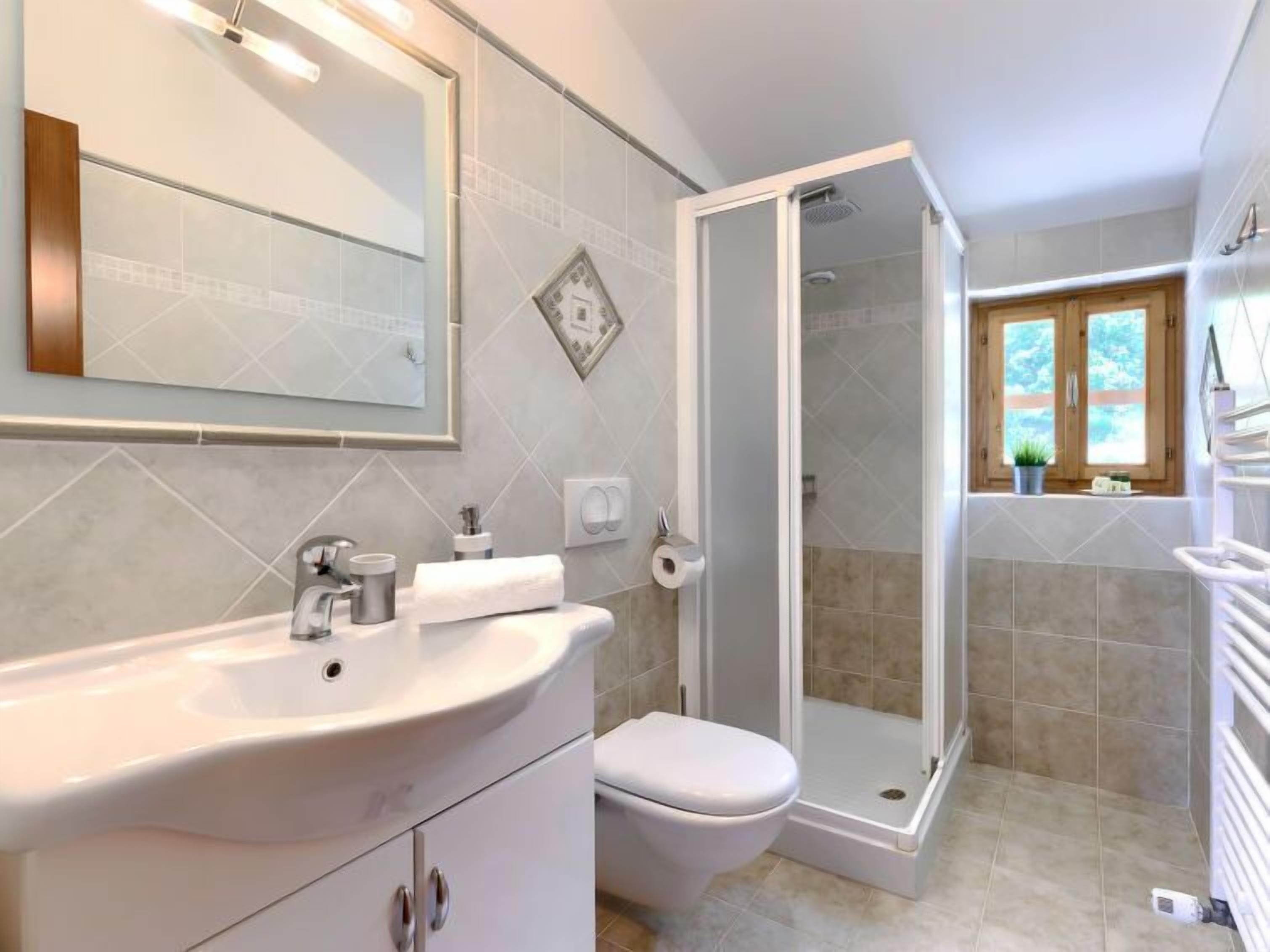 Une salle de bain avec un lavabo blanc, des toilettes et une douche fermée par une paroi de verre.