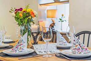 A dining table set with floral napkins, a candle, and a menu. - Welcoming holiday home in Bourton on the Water - Ross House (Bourton-on-the-Water)