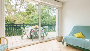 A balcony with a table and chairs, a sofa, and a view of trees. - Apartment Arnaïa by Interhome (Anglet)