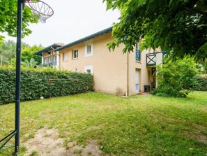 A residential building with a basketball hoop in a backyard.