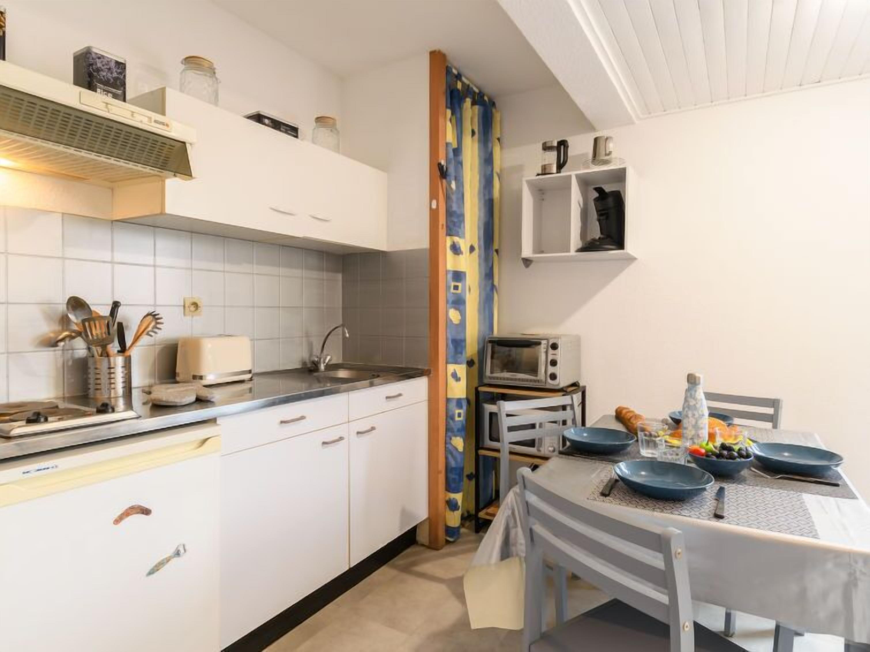 A compact kitchen with white cabinets, a sink, and a dining area with a table set for two.