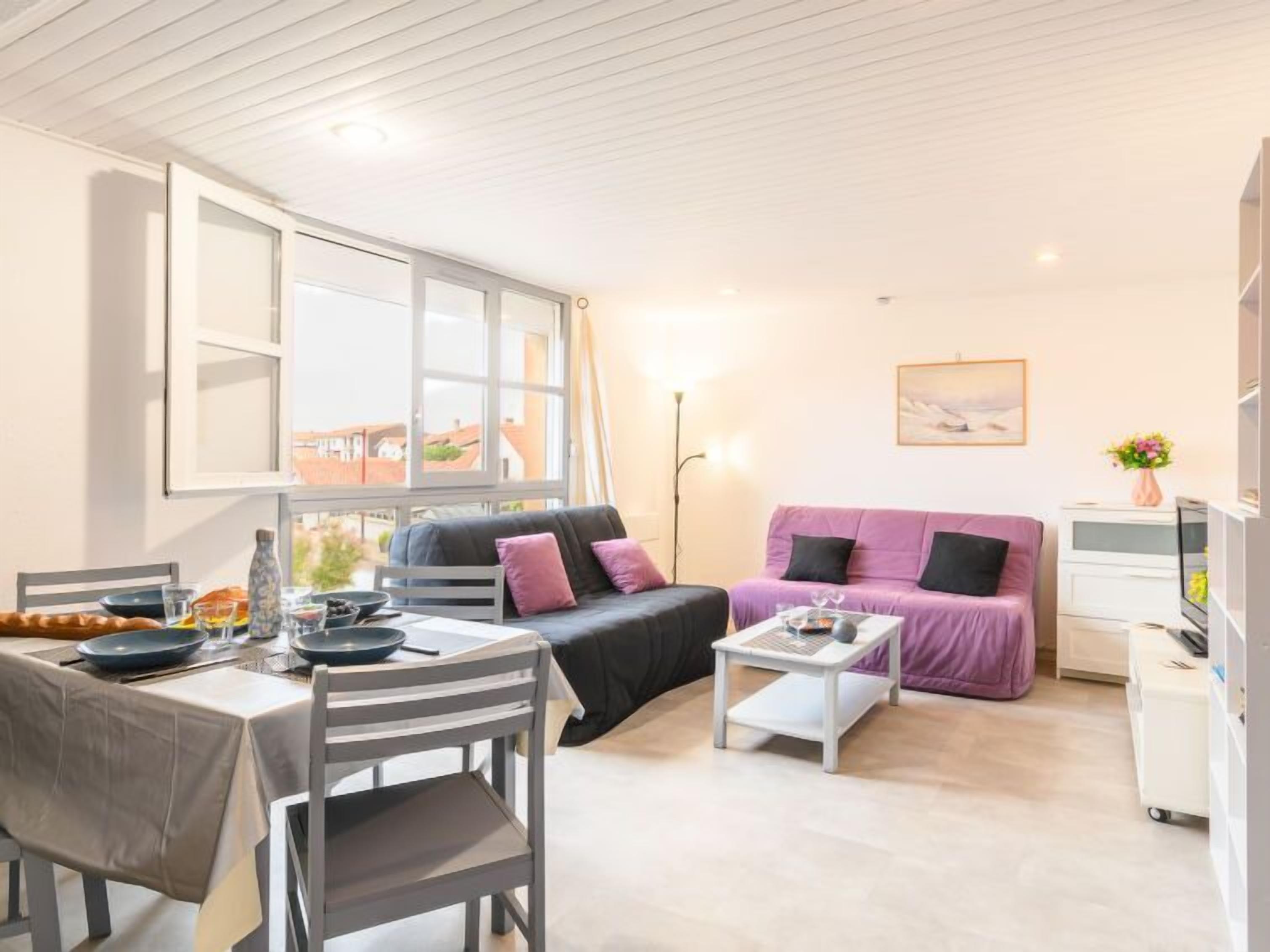 Una sala de estar moderna con comedor, un sofá, una mesa de centro y un mueble para televisión.