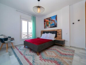A bedroom with a bed, a chair, a nightstand, a painting, and a view through a window. - Calpe Bay 04 by Interhome (Calpe/Calp)