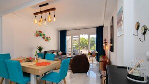 Un salon moderne avec un coin repas, comprenant une table en bois, des chaises bleues et un luminaire suspendu.
