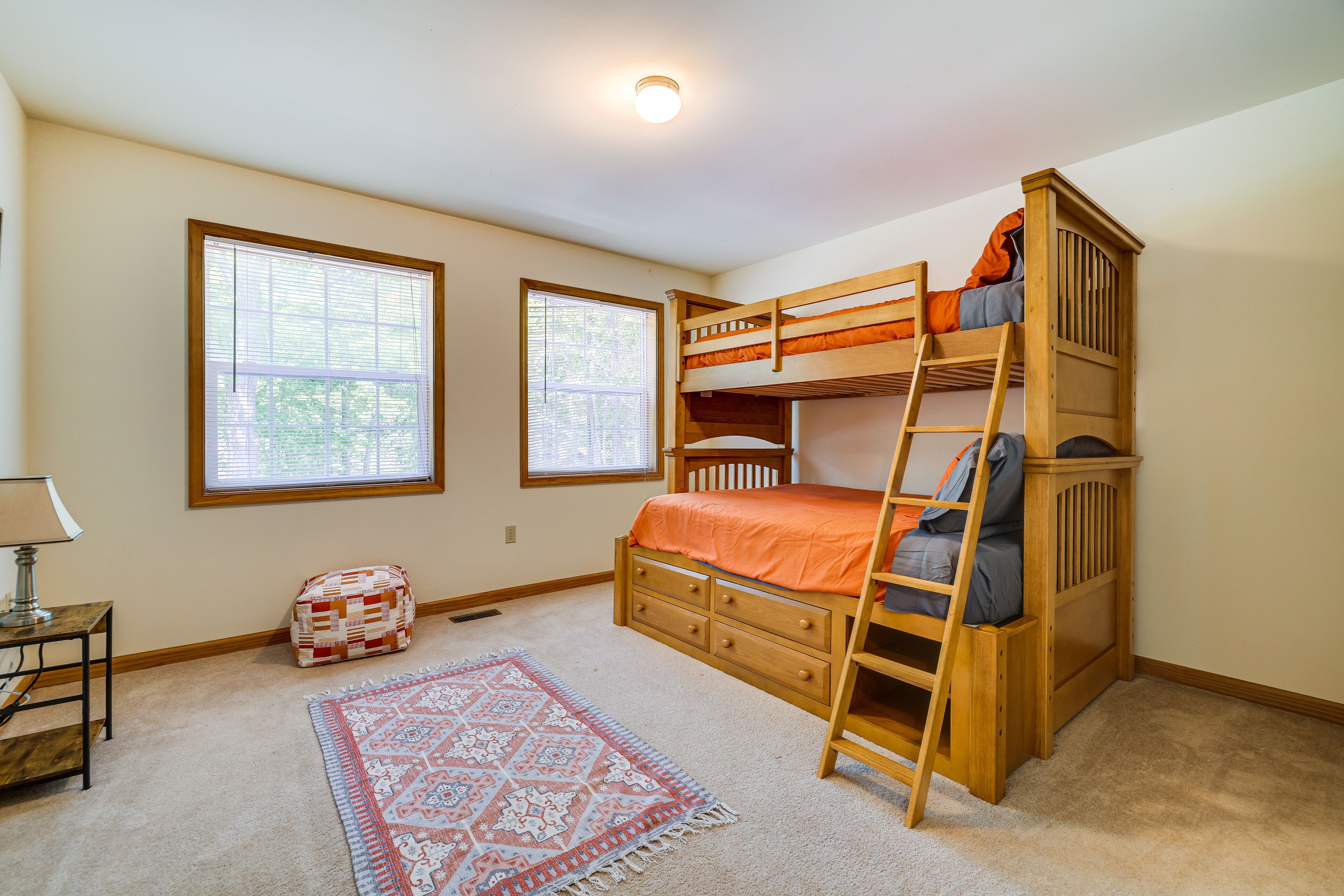 Une chambre avec un lit superposé, une fenêtre, une lampe et un tapis.