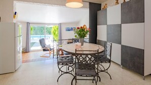 A modern kitchen with a round dining table, grey cushioned chairs, and a pendant light.