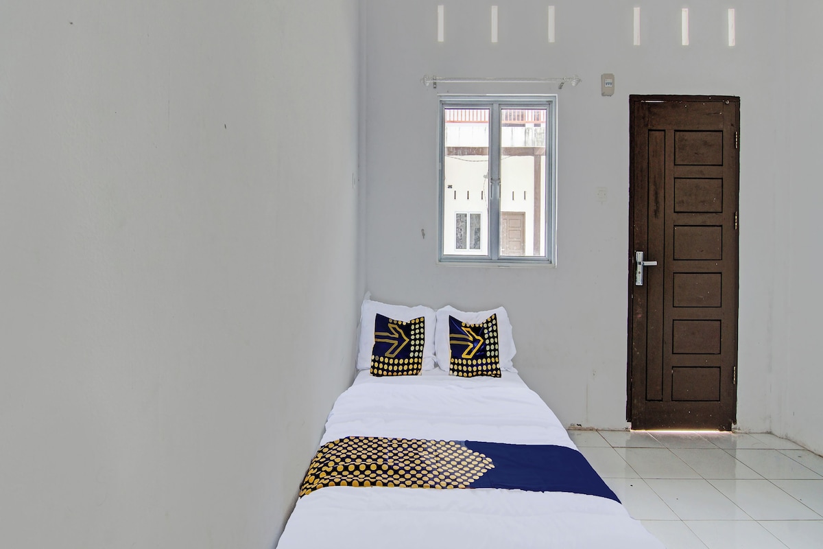 Una habitación con una cama, dos almohadas, una ventana y una puerta.