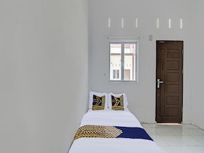 Una habitación con una cama, dos almohadas, una ventana y una puerta.