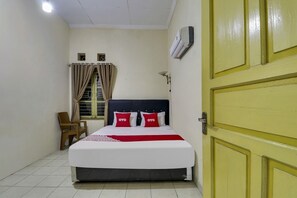 Une chambre à coucher avec un lit, une chaise, un climatiseur et une porte.