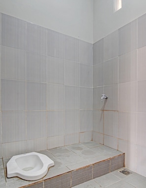 Un espacio de ducha pequeño con azulejos y un inodoro.