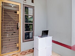 Une pièce avec une porte en bois, une fenêtre dont les vitres sont brisées et une armoire blanche sur laquelle se trouve un ordinateur portable.