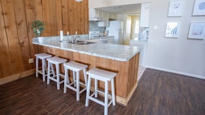Una cocina moderna con encimera de mármol, taburetes de madera y panel de pared de madera.