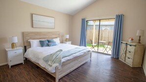 Un dormitorio con una cama grande, cabecera de madera y vistas a un patio con valla de madera.