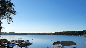 Ein ruhiger See mit Stegen, einer überdachten Bootsrampe und blauem Himmel.