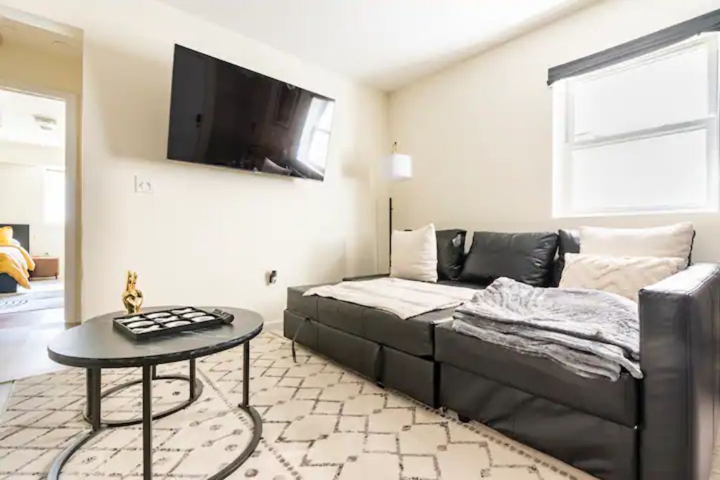 Un salon moderne avec un canapé, une table basse et un téléviseur à écran plat fixé au mur.