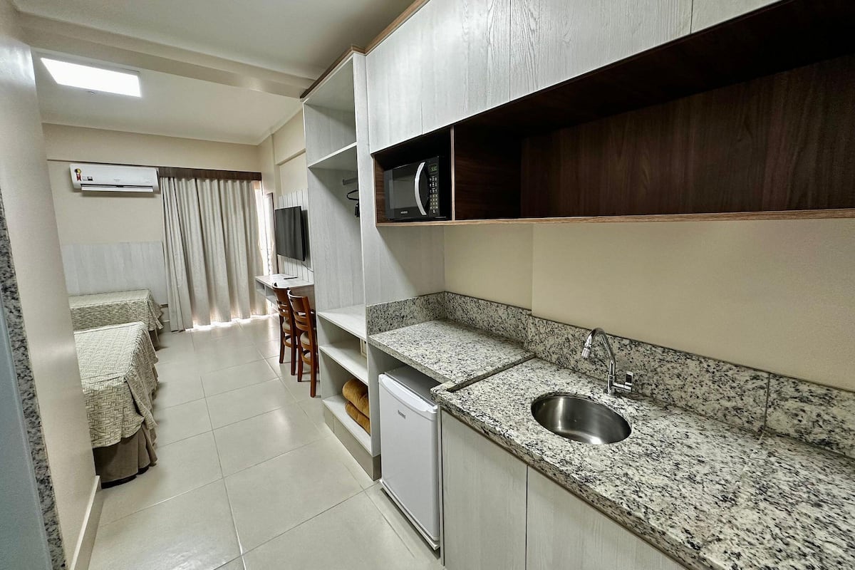 A compact kitchen with a granite countertop, stainless steel sink, and a built-in microwave.