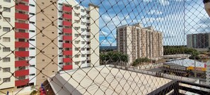 A multi-story residential building with balconies, a rooftop terrace, and a chain-link fence.