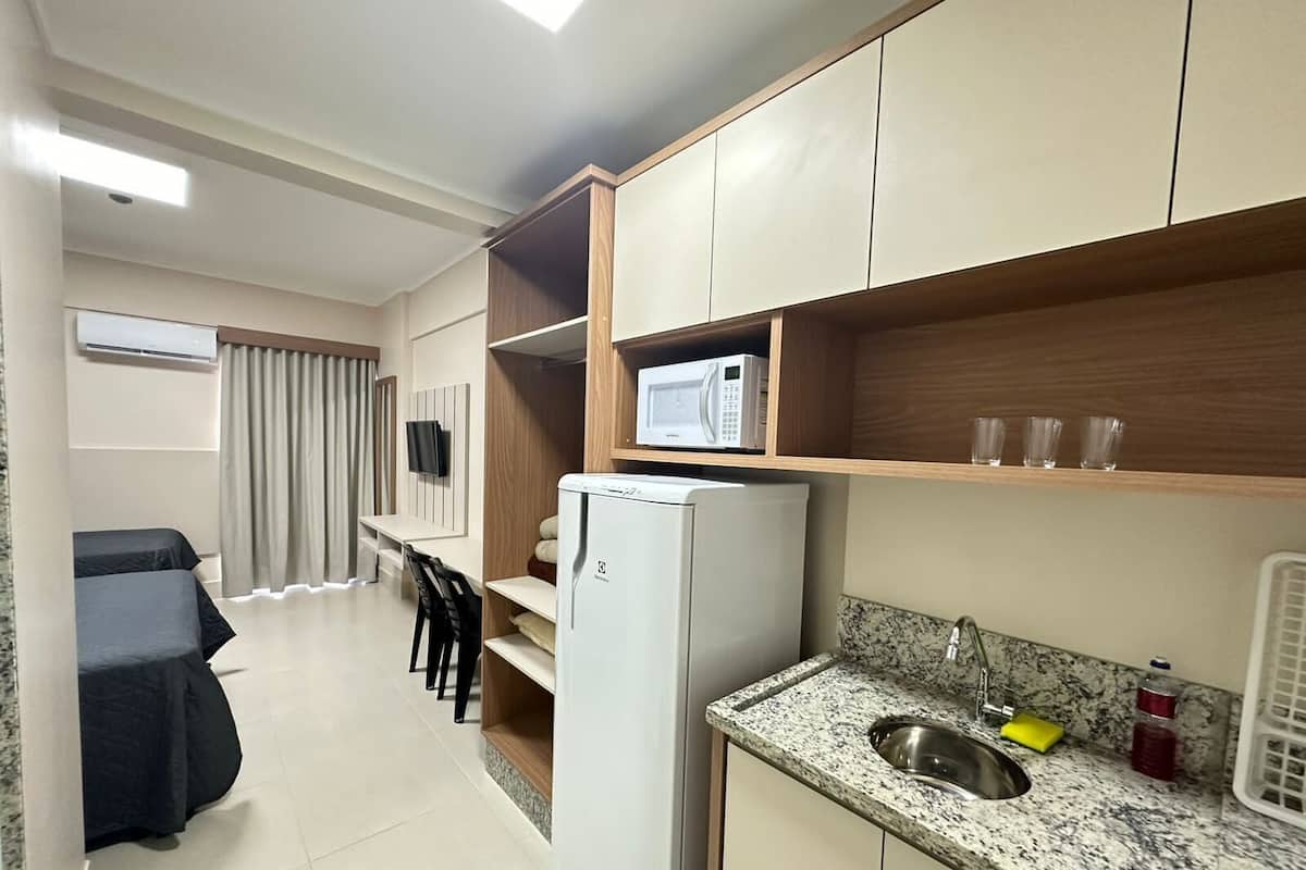 A compact kitchen with a refrigerator, microwave, and granite countertop sink.