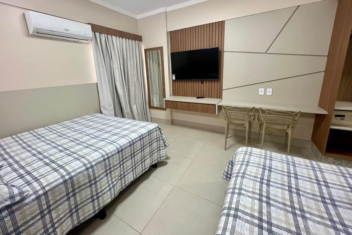 A hotel room with two beds, a TV, a desk, and a chair.