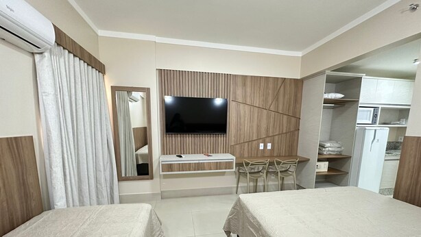 A hotel room with two beds, a TV, a desk, a mirror, and a wardrobe.
