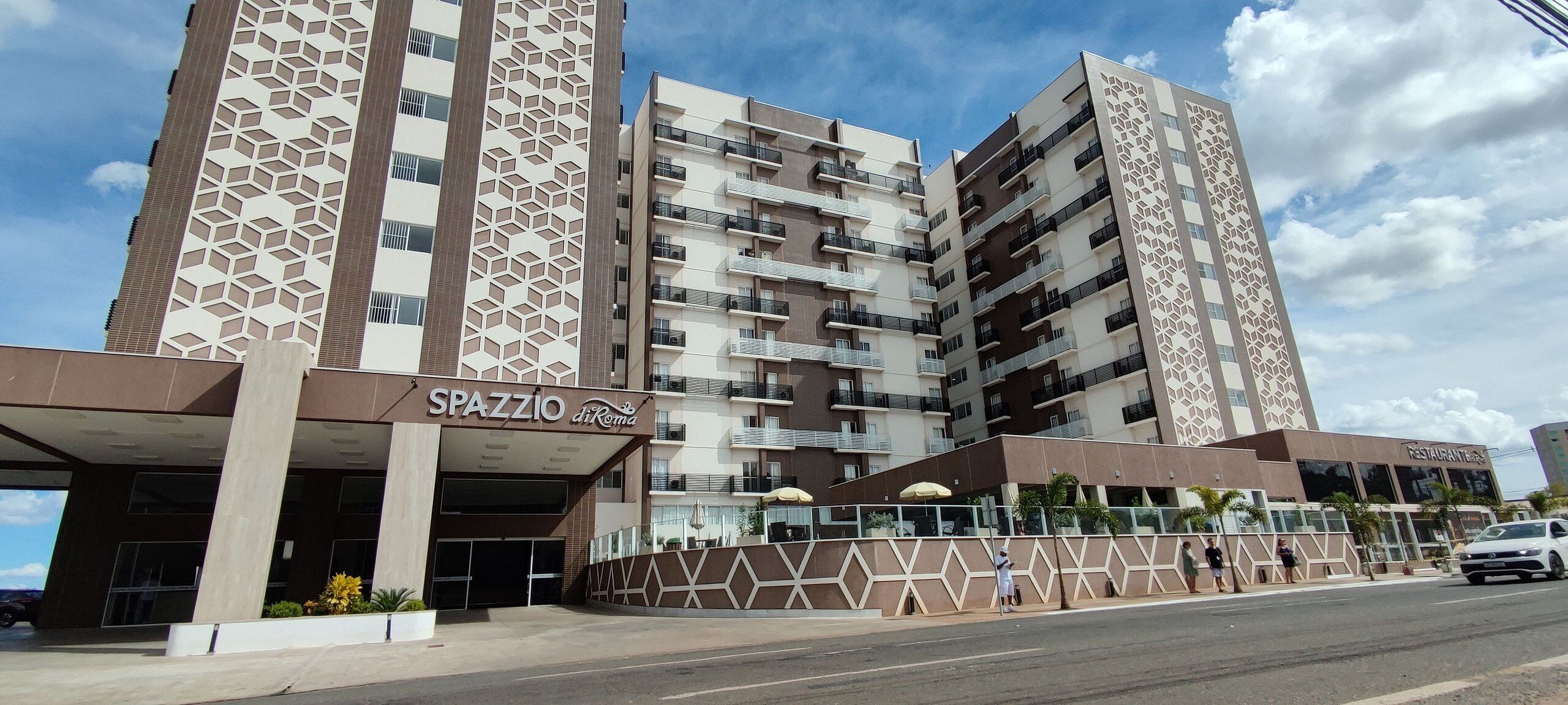 A multi-story hotel with a geometric facade, a covered entrance, and a restaurant sign.