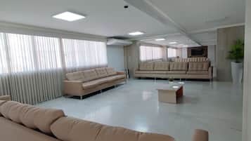 A spacious living area with a sofa, a coffee table, and a large window with blinds.
