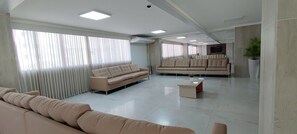 A spacious living area with a sofa, a coffee table, and a large window with blinds.