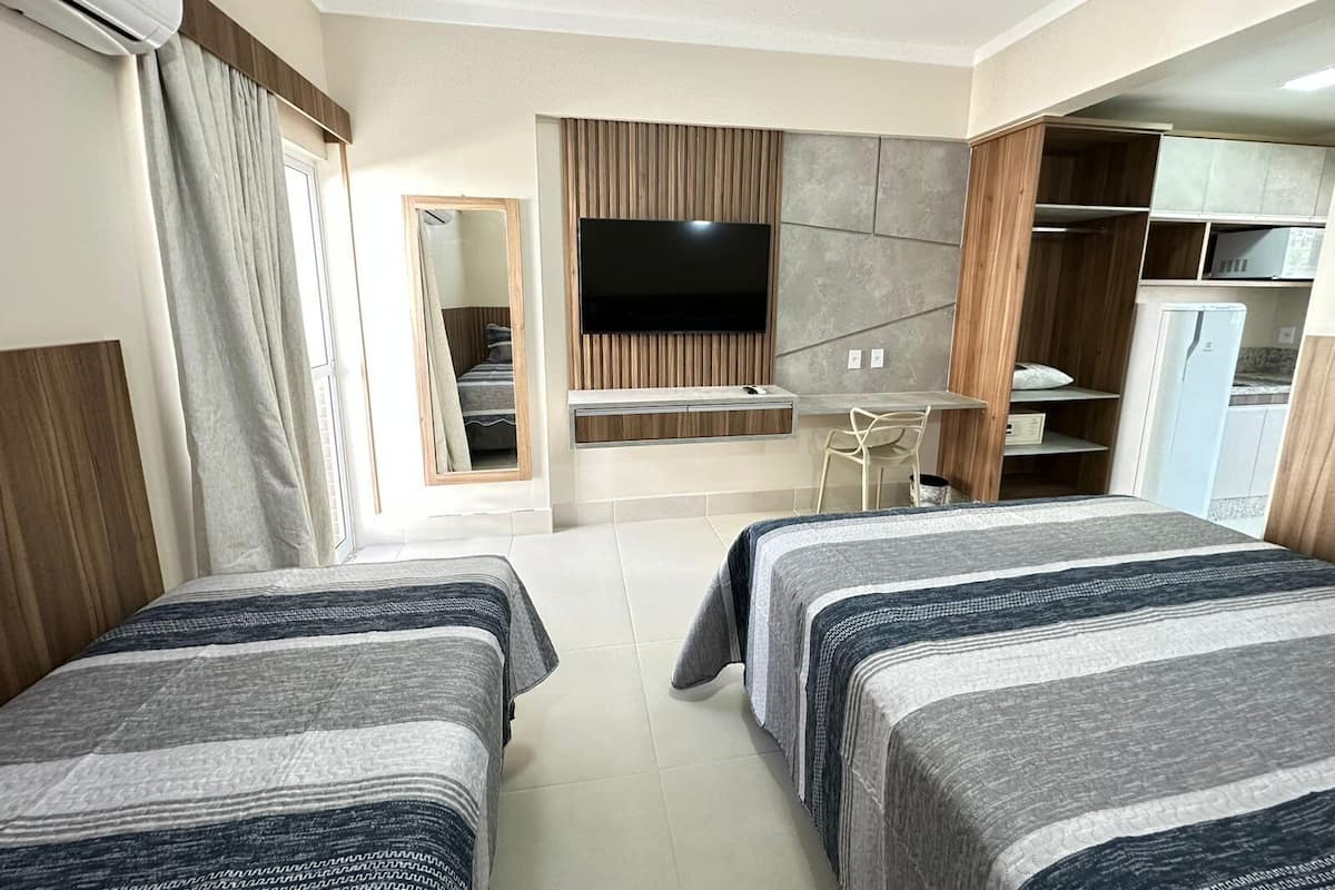 A hotel room with two beds, a TV, a desk, and a wardrobe.