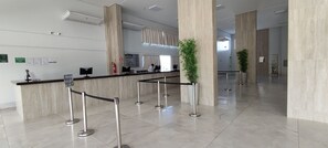 Un moderno hall de hotel con una recepción, mostradores de registro y un área de espera.