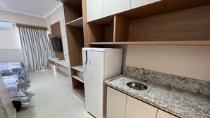 A modern kitchen with a built-in refrigerator, granite countertop, and a stainless steel sink. - Di Roma Spazzio Via Caldas (Caldas Novas)