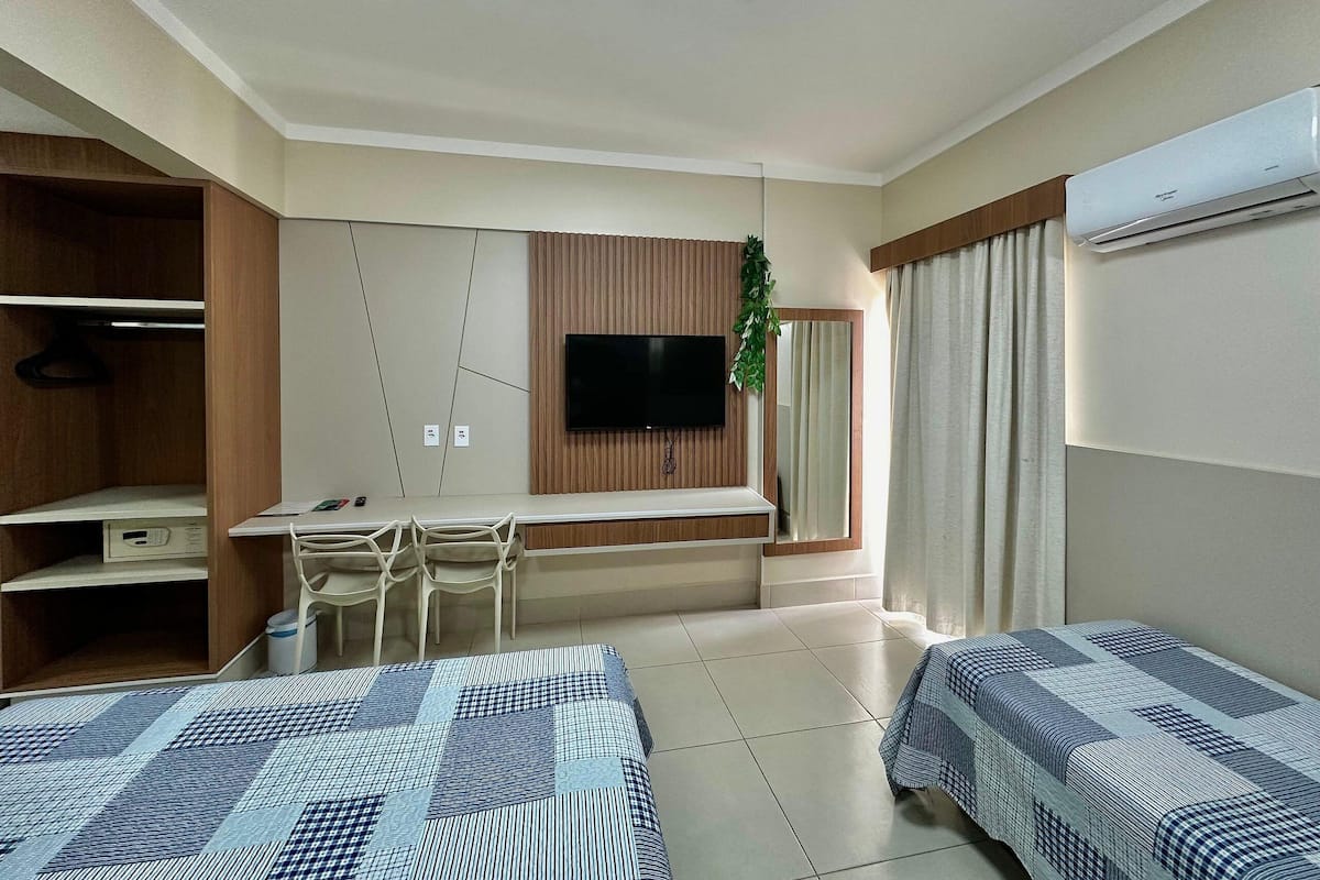 A hotel room with a bed, a desk, a TV, and a wardrobe.