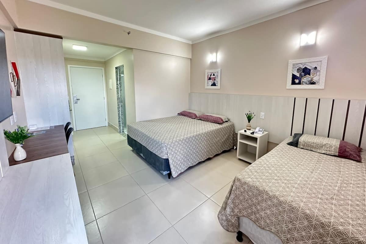 A bedroom with two beds, a bedside table with a phone, and a mirror.
